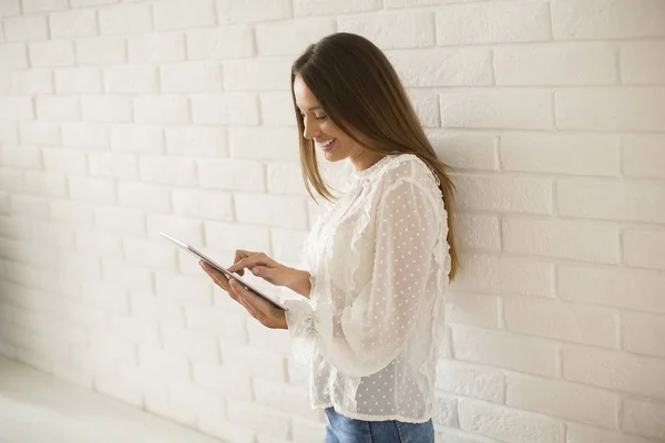 Młoda Kobieta Pomocą Cyfrowego Tabletu Przez Biała Ściana — Zdjęcie stockowe
