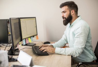 Ofiste pc bilgisayar üzerinde çalışan genç adam