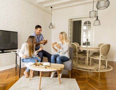 Pizza yemek ve having fun evde oturma odasında happy arkadaşlar