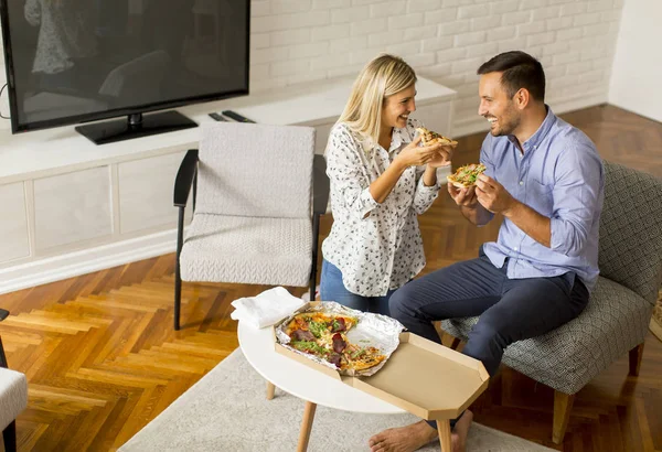 家庭でリラックスしておいしいピザを食べるカップルを愛する — ストック写真
