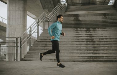 Hızlı açık havada şehirde koşan genç adam
