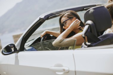 Deniz kenarında parlak güneşli Cabrio onun en iyi otomobil sürüş güneş gözlüklü genç kadın