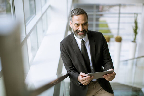 Портрет красивого старшего бизнесмена с цифровым планшетом в морском офисе
