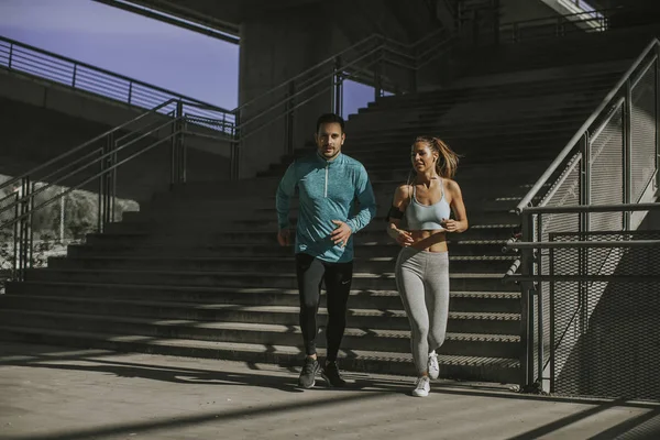 Young couple running in urban enviroment at sunny day