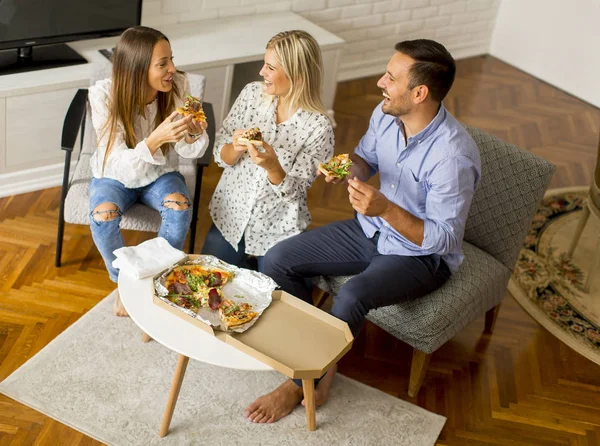 Happy friends eating pizza and having fun in the living room at home