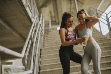 İki kadın koşucular akıllı telefon kentsel çevre koşu sonra bir arıyor