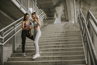 İki kadın koşucular akıllı telefon kentsel çevre koşu sonra bir arıyor