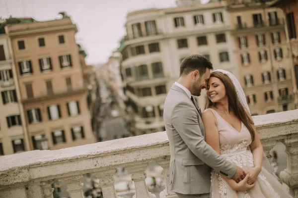 若い魅力的な新婚夫婦ウォーキングや婚礼の日の背景に美しいと古代のアーキテクチャを持つローマでポーズをとって — ストック写真