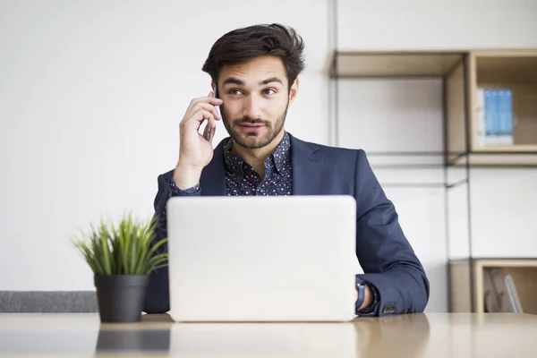 Jovem Empresário Trabalhando Laptop Falando Telefone Celular Escritório Moderno — Fotografia de Stock