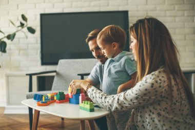 Küçük çocuk oyuncakları anne ve babayla modern evde oynarken