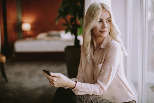 Mooie Jonge Blonde Vrouw Met Mobiele Telefoon Door Het Raam — Stockfoto