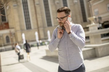 Neşeli genç adam cep telefonu kentsel çevre güneşli gün kullanır