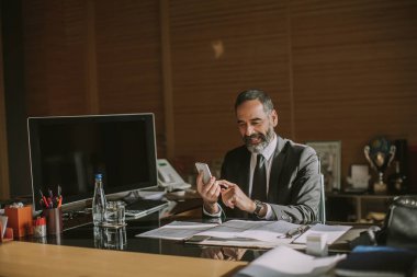 Mobila telefon kullanarak ve modern ofisinde çalışan üst düzey işadamı portresi