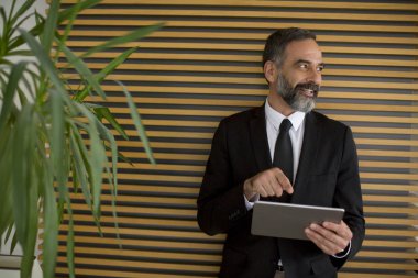 Yakışıklı orta yaş işadamı saatlerin Office dijital tablet ile