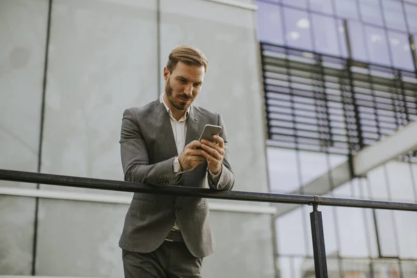 Joven Empresario Exitoso Con Traje Gris Sosteniendo Teléfono Inteligente Mientras — Foto de Stock