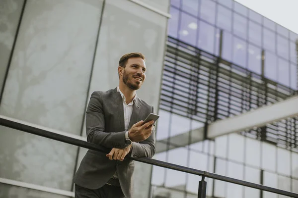 Joven Empresario Exitoso Con Traje Gris Sosteniendo Teléfono Inteligente Mientras — Foto de Stock