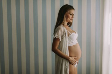 Duvar odadaki tarafından duran genç ve güzel hamile kadın