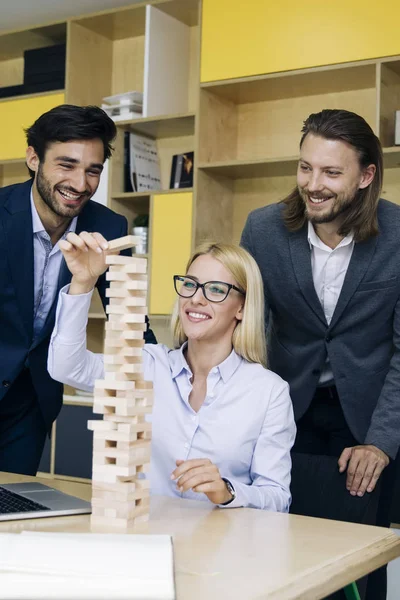 Team of young business people build a wooden construction in the office