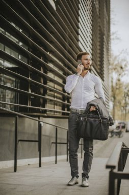 Yakışıklı genç işadamı ile hareket eden telefon ofis binası önünde yürüyüş