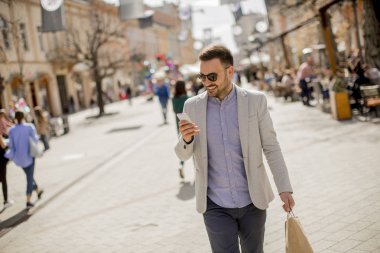 Neşeli yakışıklı adam portresi kullandığı cep telefonu ise şehirde alışveriş gidiyor