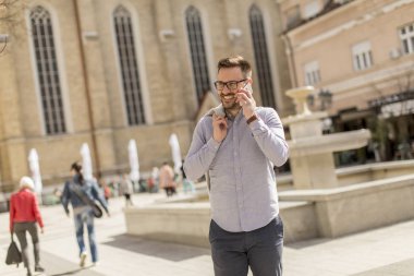 Neşeli genç adam cep telefonu kentsel çevre güneşli gün kullanır