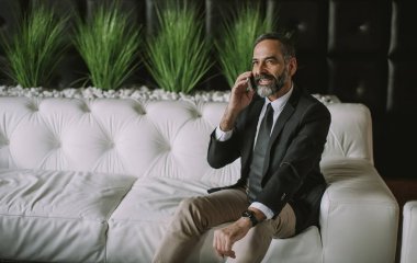 Cep telefonu kullaranarak ve ofiste kanepede oturan üst düzey işadamı portresi