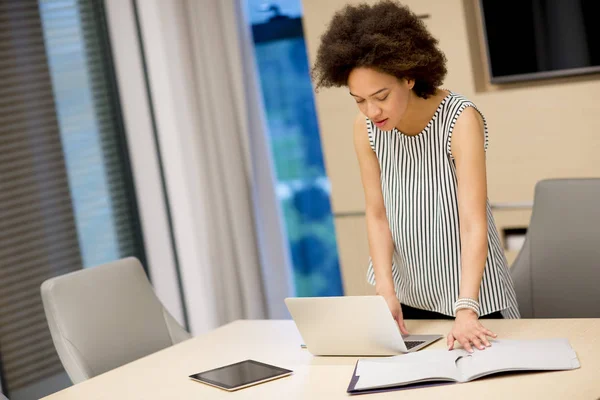 年轻的非洲裔美国妇女在现代办公室在笔记本电脑上工作 — 图库照片