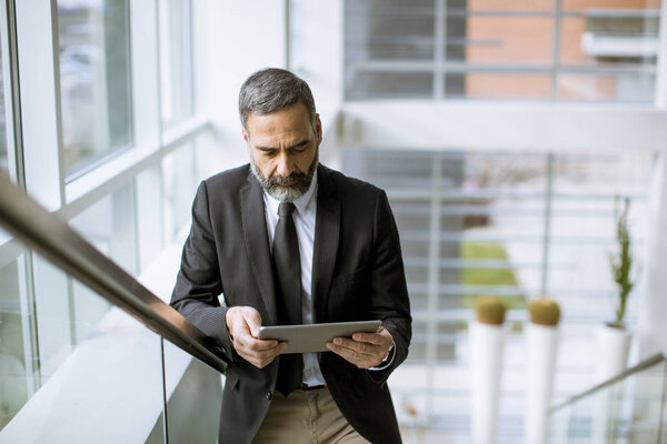Портрет красивого старшего бизнесмена с цифровым планшетом в морском офисе
