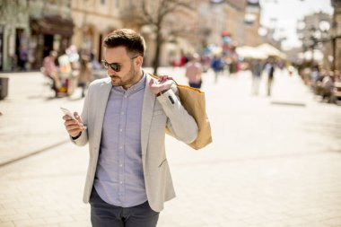 Neşeli yakışıklı adam portresi kullandığı cep telefonu ise şehirde alışveriş gidiyor