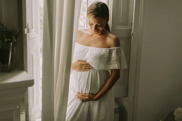 Ganska Ung Gravid Kvinna Som Står Vid Fönstret — Stockfoto