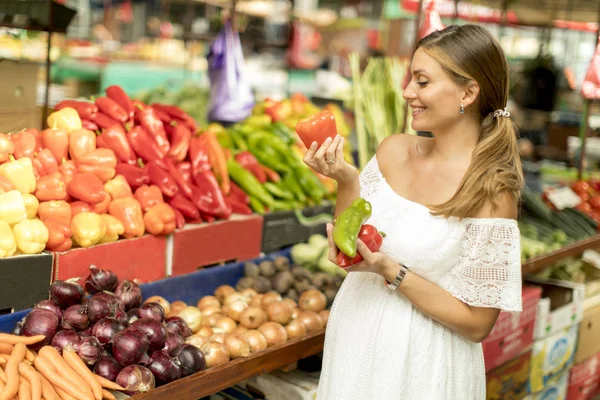 市場で新鮮な野菜を買うのはかなり若い女性 — ストック写真