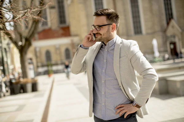 Neşeli genç adam cep telefonu kentsel çevre güneşli gün kullanır