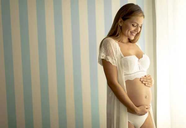 窓のそばに立っているかなり若い妊婦 — ストック写真