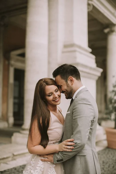 バック グラウンドで美しく 古代の建築とローマでポーズをとって魅力的な新婚カップル — ストック写真
