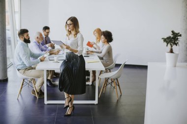 Genç çekici kadın Yöneticisi duran modern Office dijital tablet üzerinde çalışan