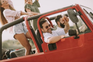 Gençlerin grup gülümseyen ve kırmızı Cabrio araba yolculuğu zevk mutlu