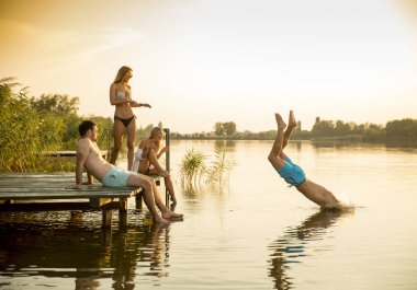 Bir grup genç insan sıcak hummer gün gölde iskelenin üzerinde eğlenceli olması