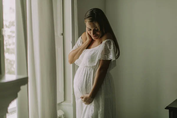 Ganska Ung Gravid Kvinna Som Står Vid Fönstret — Stockfoto