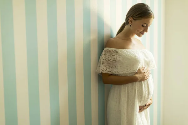 漂亮的年轻孕妇站在墙上的房间 — 图库照片