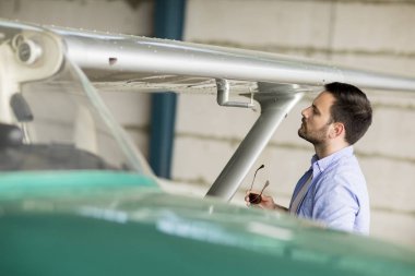 Yakışıklı genç pilot hangarda uçak kontrol