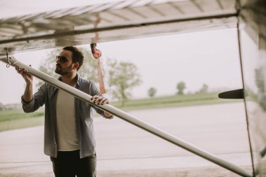 Yakışıklı genç pilot hangarda uçak kontrol