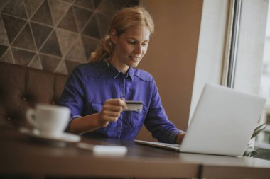 Kahve içme kafede oturan genç kadın görüntülemek ve Internet üzerinden alışveriş yapmak