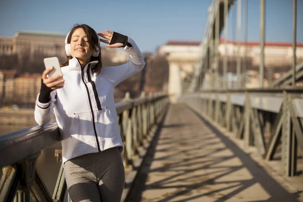 Young athlete woman with mobile phone on the bridhe in Budapest, Hungary