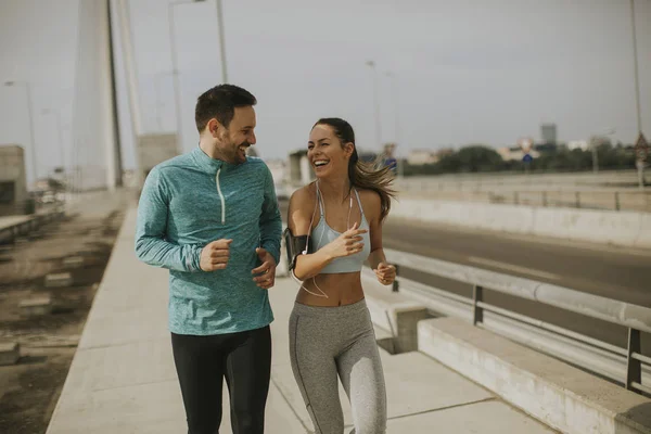 Young couple running in urban enviroment at sunny day