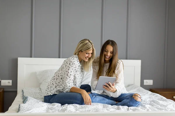 Dos Mujeres Jóvenes Con Tableta Digital Sentadas Cama Dormitorio — Foto de Stock