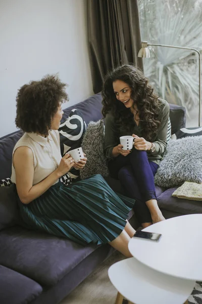 Två Raser Unga Kvinnor Chattar Och Dricka Kaffe Rhe Vardagsrum — Stockfoto