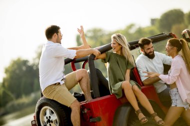 Nehir kenarındaki Cabrio araba içinde eğleniyor dört gençler