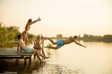 Bir grup genç insan sıcak hummer gün gölde iskelenin üzerinde eğlenceli olması