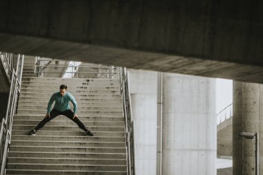 Merdivenlerde açık çalıştırdıktan sonra germe genç atletik erkek