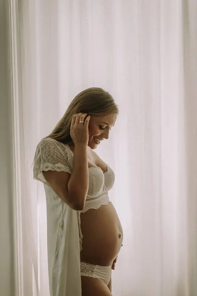 Ganska Ung Gravid Kvinna Som Står Vid Fönstret — Stockfoto